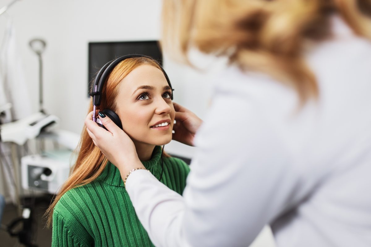 profissional da saude tira fone de exame auditivo de menina ruiva